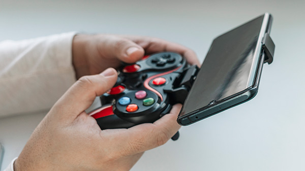un homme tenant une manette de jeu compatible avec un smartphone